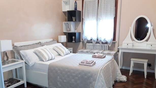 Een netjes ingerichte slaapkamer met een bed, nachtkastjes, een kaptafel met spiegel en een radiator.