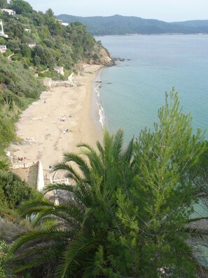 A beach with a few people, a sandy shore, and a view of the sea.