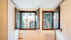 Een slaapkamer met een groot raam, een radiator en een bed met roze beddengoed.
