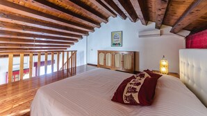 A bedroom with a wooden ceiling, a bed with a white headboard, a nightstand with a lamp, and a cabinet. - Novalesi House (only 20 minutes to Venice) (Noale)