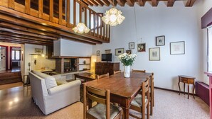 A spacious living area with a wooden dining table, a sofa, and a kitchen in the background. - Novalesi House (only 20 minutes to Venice) (Noale)