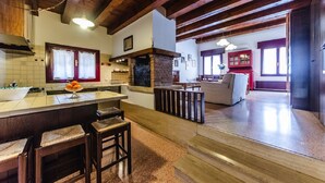 A spacious kitchen with a central island, wooden beams, and a red cabinet in the background. - Novalesi House (only 20 minutes to Venice) (Noale)