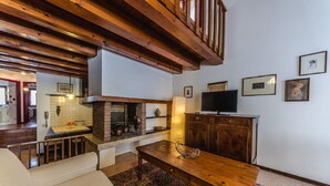 A cozy living room with a wooden table, a sofa, a fireplace, and a television. - Novalesi House (only 20 minutes to Venice) (Noale)