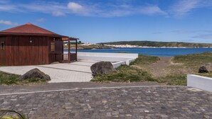 Un bâtiment situé sur la côte, avec un toit rouge, une promenade dallée et une vue sur la mer.
