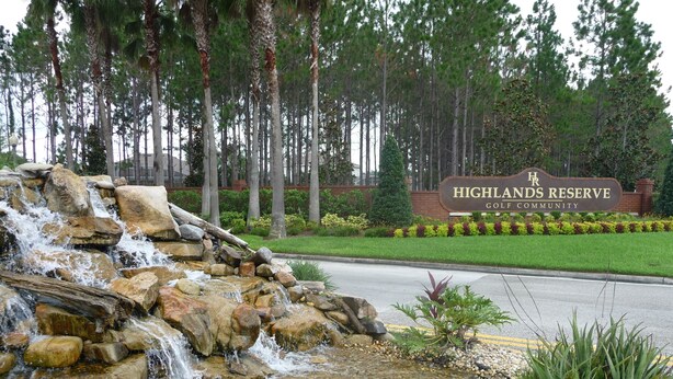 Et vandfald i en anlagt park med skilt for Highlands Reserve Golf Community.
