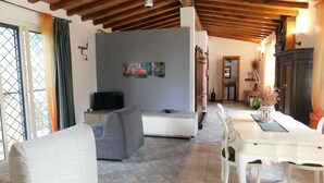 A living room with a TV, sofa, and dining table. - Domus Anghelos ... in the Roman countryside (Roma)