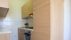 A kitchen with wooden cabinets, a gas stove, and an oven. - three-room apartment in a beachfront condo with a view of the pedestrian walkway (Comacchio)