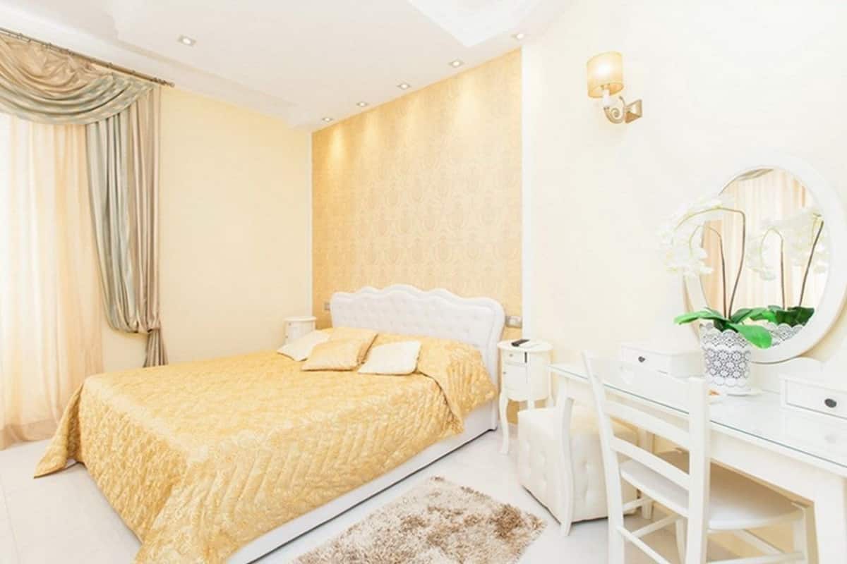 A bedroom with a bed, bedside tables, a dresser, and a mirror.