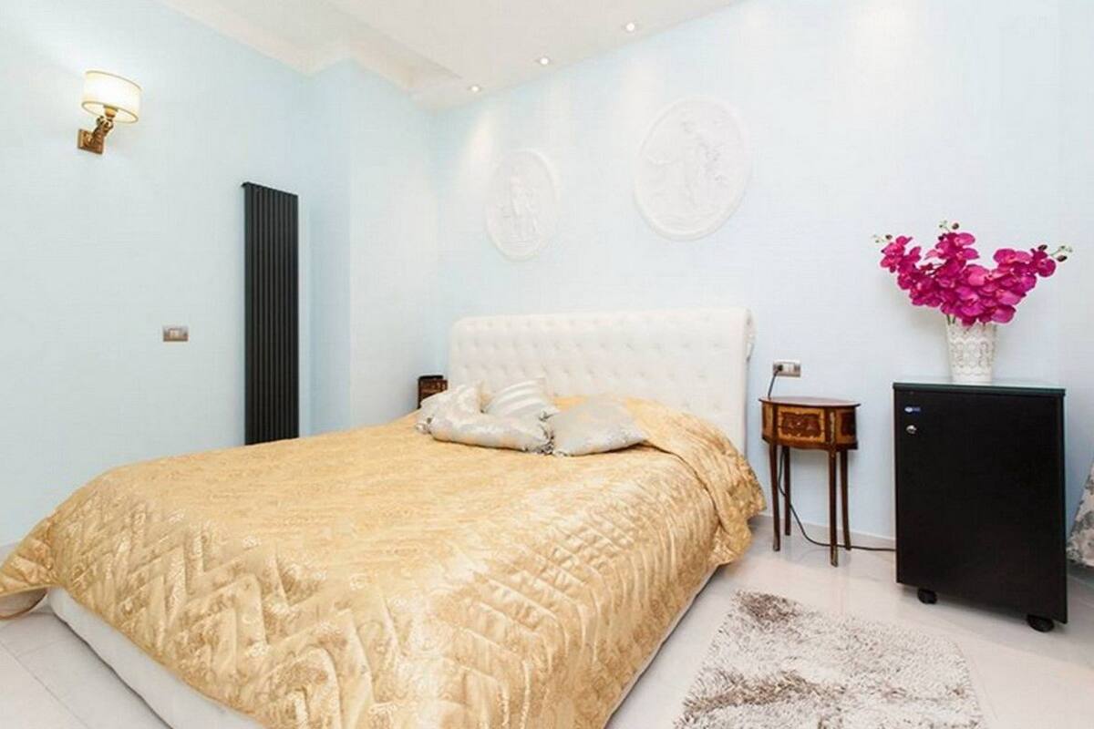 A bedroom with a large bed, a bedside table, a lamp, and a small cabinet.