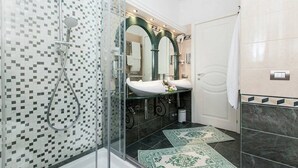 A modern bathroom with a glass shower enclosure, a sink with a mirror above, and a tiled floor. - Impero Vaticano San Pietro (Rome)
