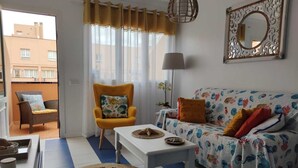 Sala de estar com sofá, poltrona, mesa de centro e manta estampada.