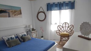 Quarto com cama, cadeira, luminária e um adorno na parede.