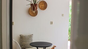 Ein Zimmer mit einem runden Tisch, einem weißen Stuhl, einer hängenden Makrameepflanze und einer gewebten Wanddekoration.