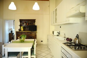 Una cocina compacta con mesa de comedor, estufa, microondas y pileta.