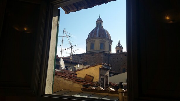 A view through a window of a building with a large dome and a bell tower, indicating a historical or religious structure. - SweetHome S.Frediano 3bdr (Firenze)