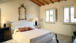 A bedroom with a bed, bedside lamps, a mirror, and windows. - SweetHome S.Frediano 3bdr (Firenze)