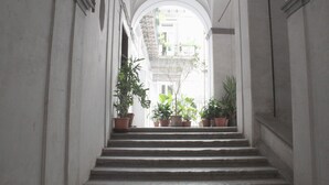 A narrow staircase with potted plants on the steps, leading to an archway. - Luxurious apartment in an ancient noble palace in the historic center of Naples (Napoli)