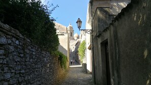 A narrow cobblestone street flanked by stone walls and buildings with domed roofs. - Liberty apartment (Erice)