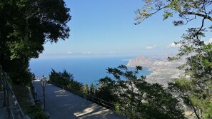A paved pathway with benches, surrounded by trees, leading to a scenic overlook with a view of the sea and distant mountains. - Liberty apartment (Erice)