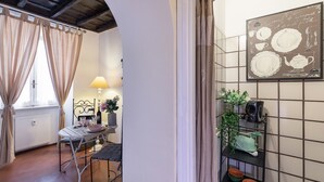 Uma área de refeições com uma mesa posta para dois, uma luminária e um quadro de cardápio fixado na parede.