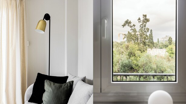 A modern living room with a sofa, a floor lamp, and a view of a balcony with greenery and buildings. - UPSTREET Zeus Temple View 2BD Apt Acropolis-Plaka (Athens)