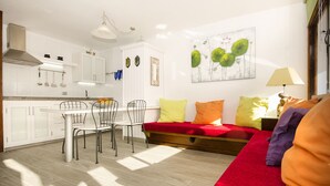 Eine moderne Küche mit weißen Schränken, einem Esstisch mit Stühlen und einem roten Sofa mit Kissen.