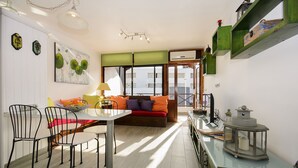 Ein modernes Wohnzimmer mit Essbereich, ausgestattet mit einer Couch, Sesseln, einem Tisch und einer dekorativen Laterne.