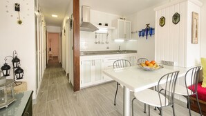 Eine moderne Küche mit weißen Schränken, einer Edelstahl-Dunstabzugshaube und einem Essbereich mit weißem Tisch und Metallstühlen.