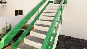 Eine Treppe mit grünen Geländern, die zu einem Hauseingang führt.