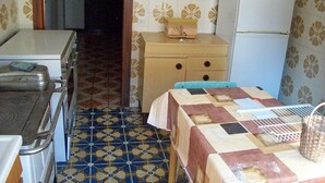 A compact kitchen with a patterned floor, a refrigerator, a wooden cabinet, and a table with a checkered tablecloth. - sweet home sabina    (Montopoli di Sabina)