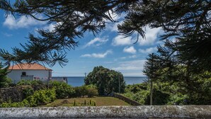 A coastal view with a white building, a stone wall, and a bench.