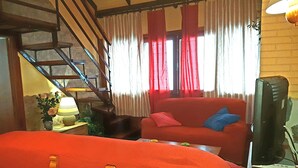 A room with a red sofa, a wooden chair, a TV on a stand, a lamp, and a staircase. - Duplex dream on the slopes in the Sierra Nevada, Pradollano (Sierra Nevada)