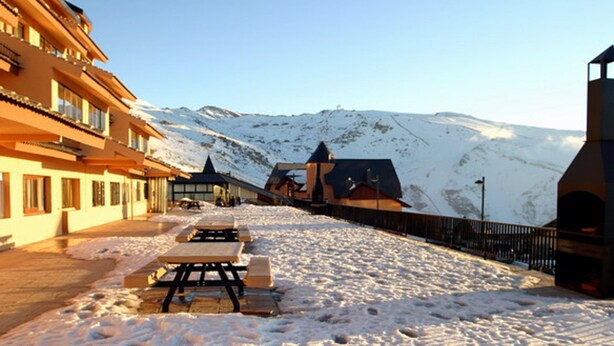 A snow-covered outdoor area with picnic tables and a building with balconies. - Duplex dream on the slopes in the Sierra Nevada, Pradollano (Sierra Nevada)
