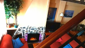 A cozy living room with a fireplace, red and blue cushions, a television, and a staircase. - Duplex dream on the slopes in the Sierra Nevada, Pradollano (Sierra Nevada)