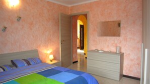 A bedroom with a bed, bedside table, dresser, and a door leading to another room. - Casa Gabriella apartment with lake view (San Siro)