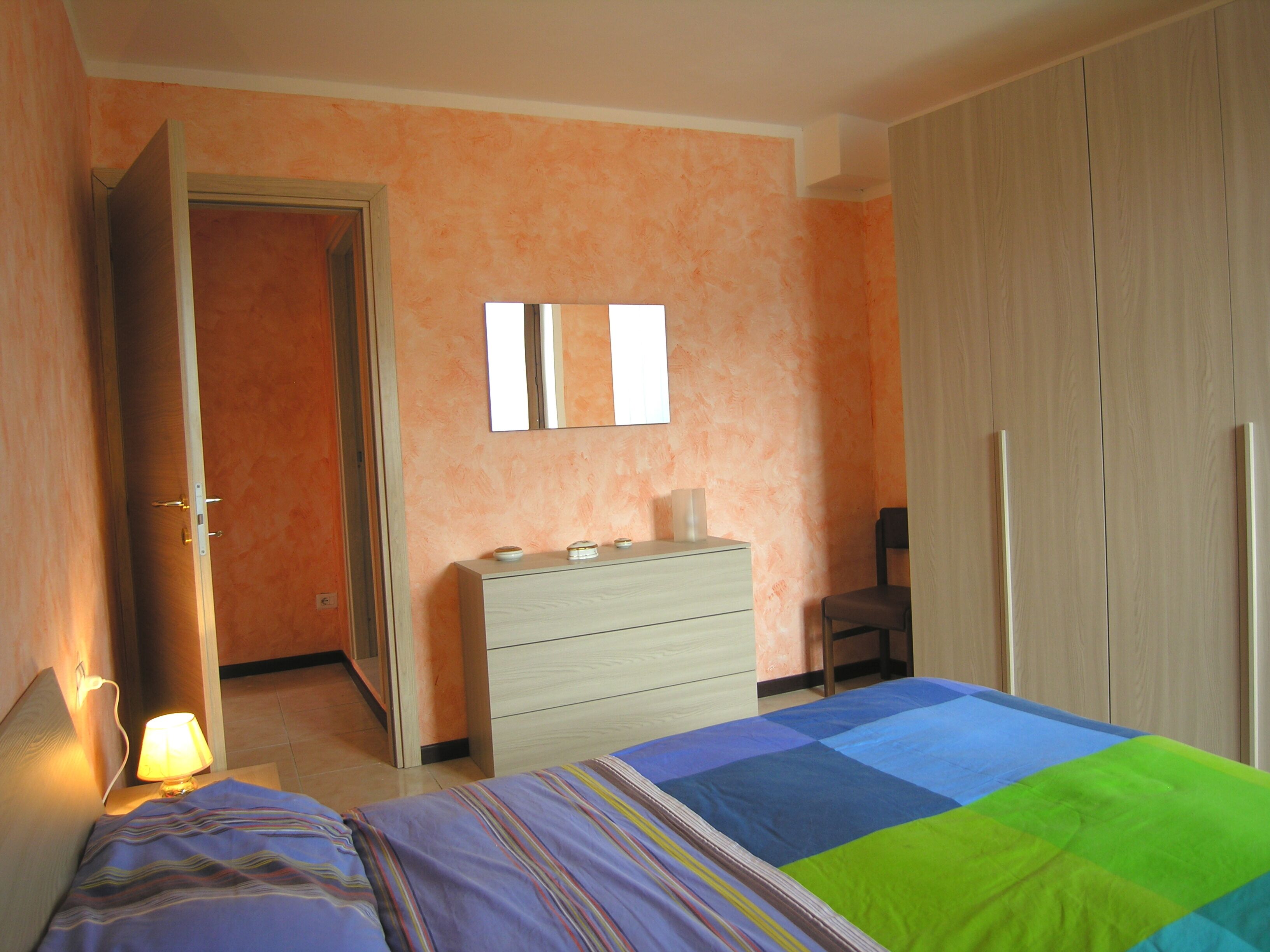 Ein Schlafzimmer mit Bett, Kommode, Stuhl und Kleiderschrank.