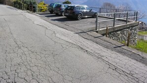 A parking area with cars parked on a sloped road, overlooking a mountainous landscape. - Casa Gabriella apartment with lake view (San Siro)
