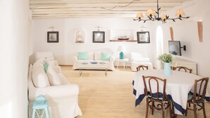 Un salón espacioso con un sofá blanco, una mesa de comedor con sillas y una araña.