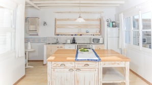 Una cocina con una isla de madera, armarios blancos, un microondas y una lámpara colgante.