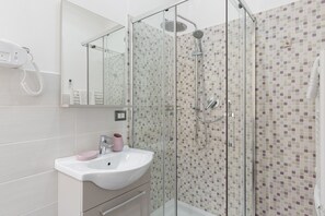 Une salle de bain moderne avec une douche à parois de verre, un lavabo blanc et un miroir.