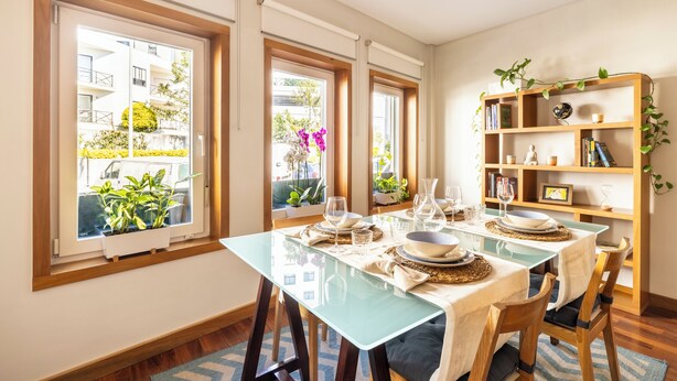 A dining area with a glass table, chairs, and a bookshelf with books and decorative items. - Spacious Downtown Apartment with Private Terrace (Porto)