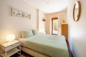 A bedroom with a bed, nightstand, dresser, and a window with curtains. - Spacious Downtown Apartment with Private Terrace (Porto)