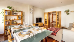A modern living room with a dining area, wooden furniture, a television, and a bookshelf. - Spacious Downtown Apartment with Private Terrace (Porto)