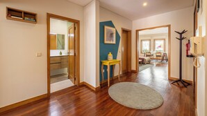 A hallway with wooden flooring, a round rug, a wooden bench, and a framed picture on the wall. - Spacious Downtown Apartment with Private Terrace (Porto)