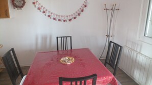 A dining area with a red table, black chairs, a Christmas garland, and a coat rack.