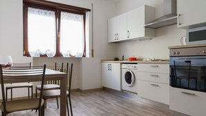 A compact kitchen with a dining area, featuring a washing machine, oven, and cabinets.