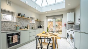 A modern kitchen with a skylight, built-in appliances, and a dining area with a table and chairs.