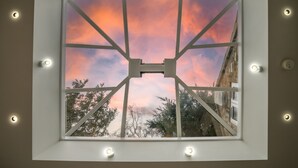 A skylight with a view of a sunset sky and surrounding trees.