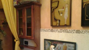 A kitchen with a wooden cabinet, a framed advertisement, and a bowl of fruit on a table. - ROMANTIC PERFECT FOR CATHEDRAL & EXHIBITION (Milano)