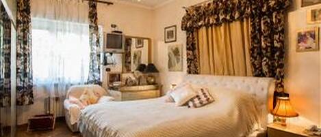 Une chambre à coucher avec un grand lit, une table de chevet avec une lampe, une commode et un miroir.